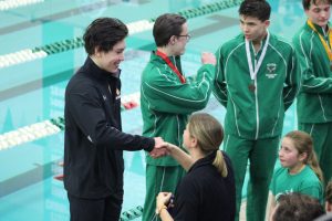 Hayden Zheng accepts first place medal for his performance in the 200 IM. The award was presented to him by math teacher Amanda Forsberg. The time of 1.56.1 minutes and place qualified him for the State meet March 1 and 2.