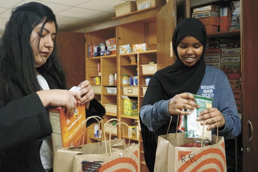 Juniors Victoria Martinez and Mushtakh Mohammad pack bags March 7, for students in need of food. The Birdfeeder is accepting applications for students who rely on school breakfast and lunch and wont have access to food during spring break.