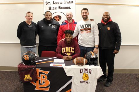 Senior Milkaso Dedefo signs his commitment to play football at the University of Minnesota Crookston on Feb. 6. Dedefo was accompanied by his teammates, coaches, family and friends.
