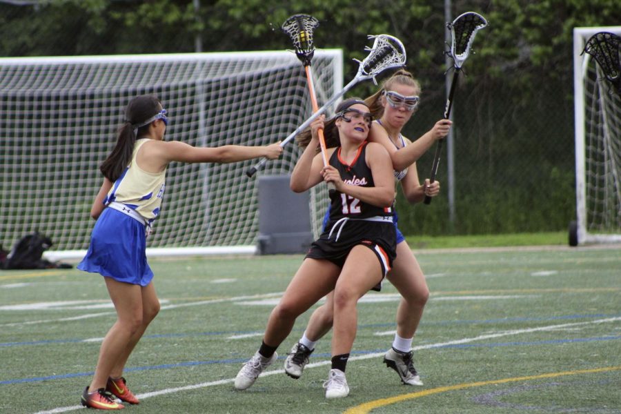 Junior Sarah McCallon pushes her way past an opposing team player to pass the ball during the 2018 lacrosse season. During the 2019 season the locker rooms will be under construction and spring sports need to find a place to change before practice. 