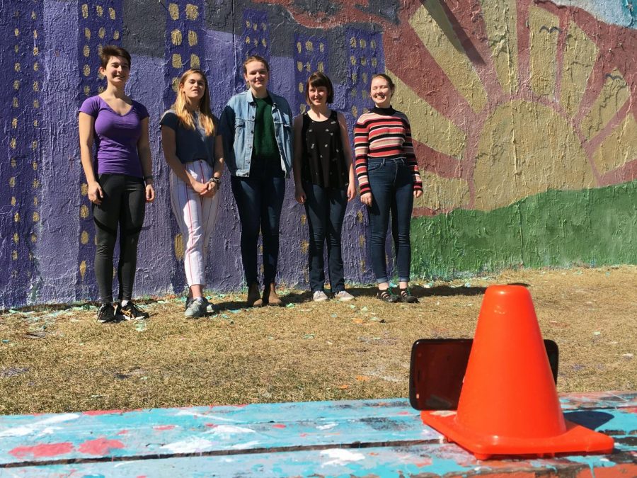The day after painting the wall on the track shed, seniors Greta Long, Sophia Davenport, Ilsa Olsen, Caroline Garland and Katie Christiansen create a video for a Technovations project. Roots and Shoots painted the wall April 18.