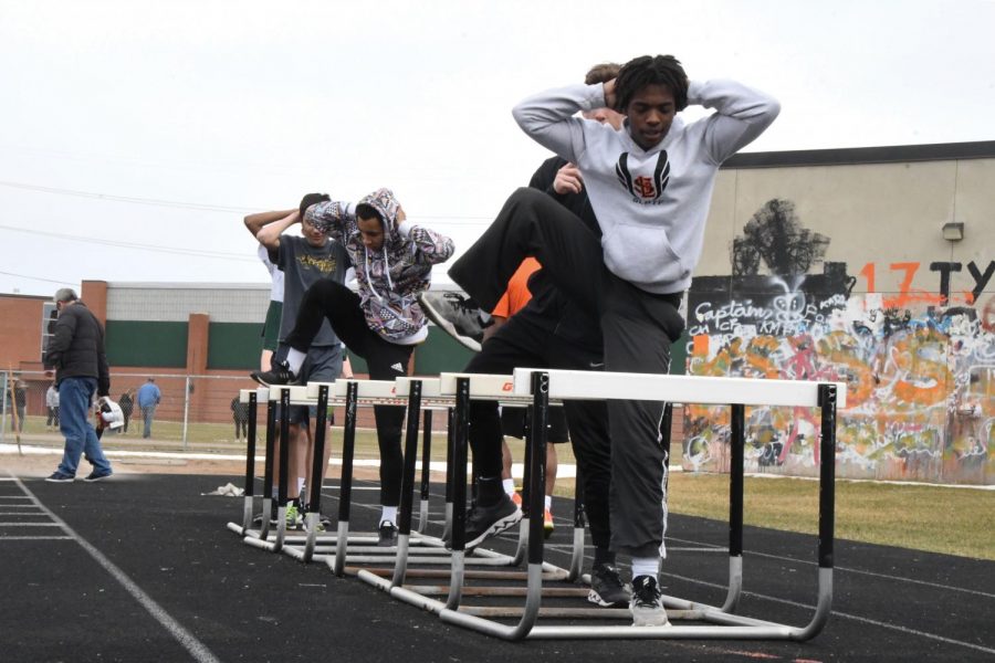 Senior Donovan Hill practices with his fellow track teammates by walking over hurdles before running. The recent snowstorm April 11 caused the team to again be indoors. 