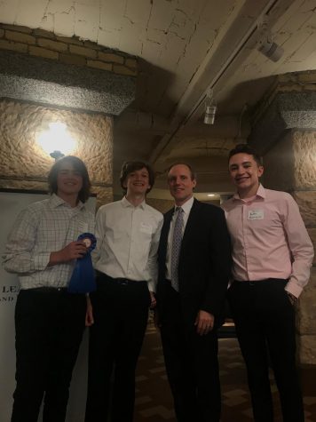 Freshmen Tommy Tight, Adam Gips and Andre Barajas pose with Minnesota Secretary of State Steve Simon. Freshman civics students were selected to present their Project Citizen poster boards at the state capitol May 15.