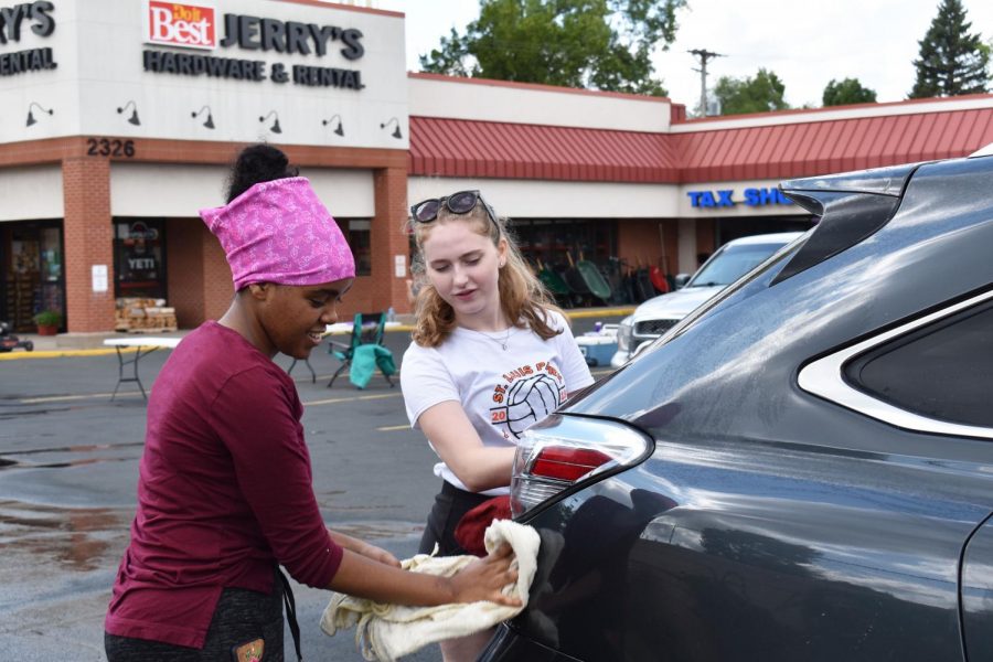 Sophomore Lily Nugteren and junior Helen Tefera dry off a car at the carwash fundraiser Aug. 25. The fundraiser was held at Jerrys Hardware Store on Louisiana Ave.