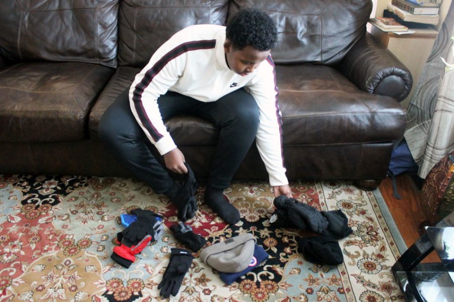 Sophomore Adil Ade organizes hats and gloves to prepare for his next project Nov. 20. His organization Pocket Change Foundation helps the homeless.