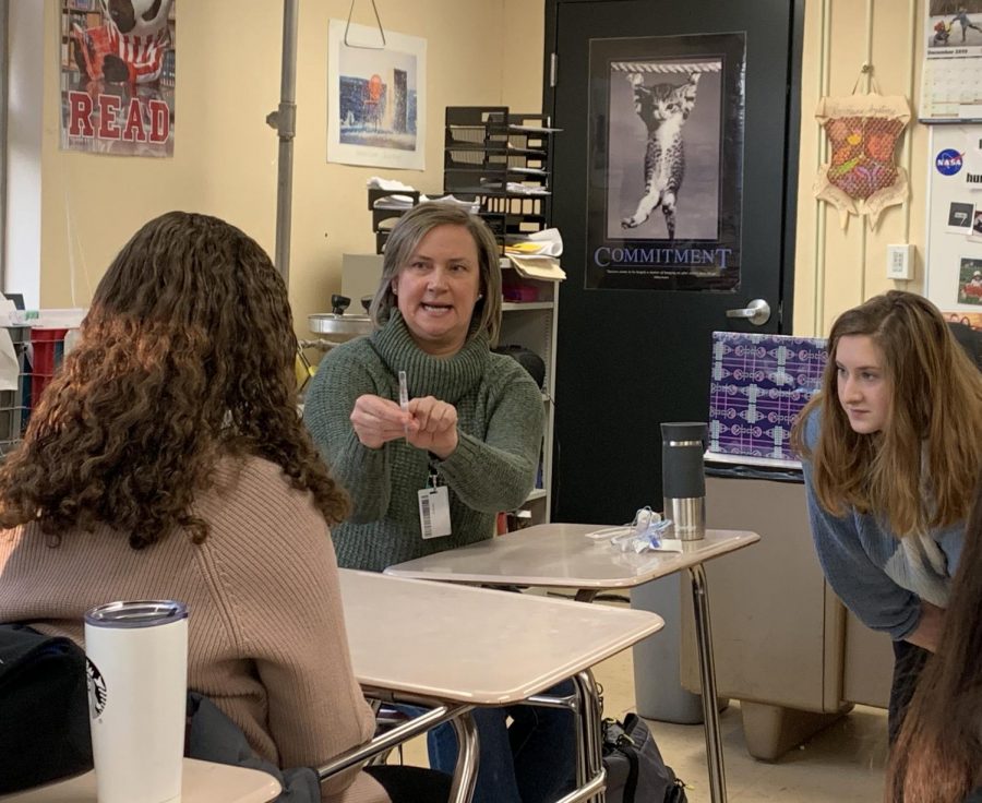 Home care nurse Heather Mcleod describes how to put an IV in to senior Emma Tight. Med club invited Mcleod to speak to students about her profession at the club meeting Dec. 17.