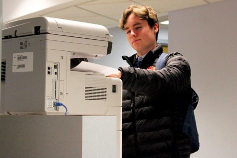 Senior Blake Grant grabs a piece of paper from the student printer Dec. 2 in the At-Large Lab. According to librarian Ellen George, students and teachers now use separate printers.