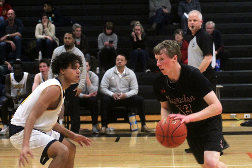 Senior Erick Piehl dribbles the ball against a Kennedy defender during the game against Bloomington Kennedy Feb 4. The game ended with the score 47-44. 