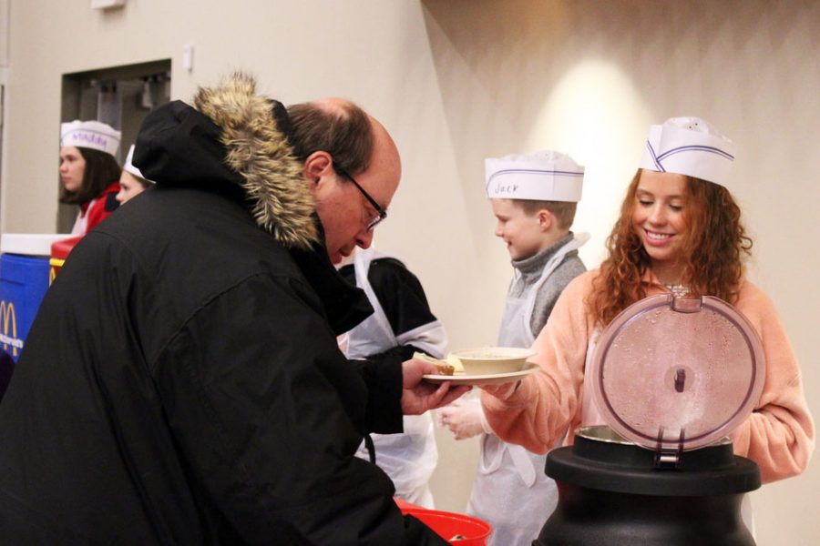 Junior Katie Casey hands a bowl full of soup and bread to a St. Louis Park citizen Feb. 13. Casey volunteered at the STEP Empty Bowls event alongside many Park students.