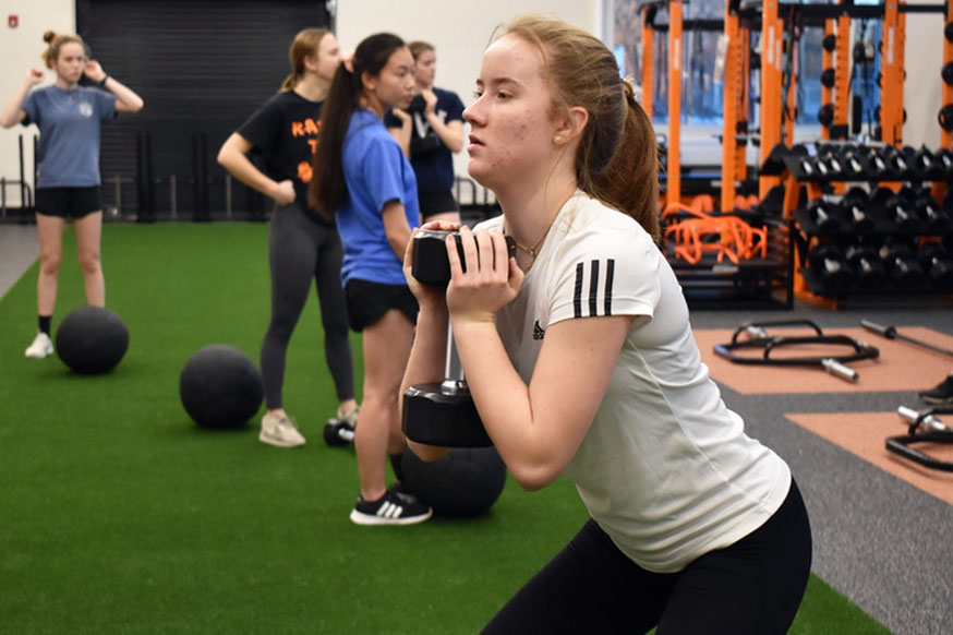Sophomore Theresa Haerke does a goblet squat in the new weight room March 10. The new weight room was installed in order improve the strength and conditioning program for athletes.
