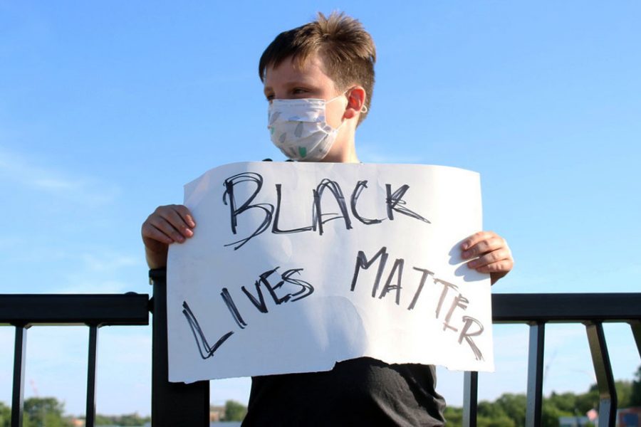 A child wearing a mask holds a Black Lives Matter sign. In the invitation to the memorial, organizers urged participants to wear masks and follow social distancing.