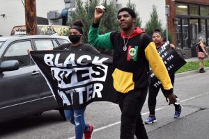 Two protesters show strength with one carrying a “Black Lives Matter” flag while the other raising a fist. Following the death of George Floyd May 25, protesters gathered to honor Floyd and fight against police violence. 