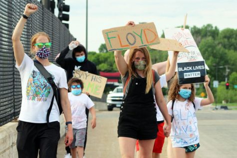 A group of protesters June 4 walk across a bridge on Louisiana Ave. holding signs that say “Floyd” and “Black Lives Matter.” Protesters gathered for the “SLP: Honoring George Floyd - peaceful/socially distant gathering” at the pedestrian bridge on Wayzata Blvd between Winnetka and Louisiana and the Louisiana Ave. bridge.