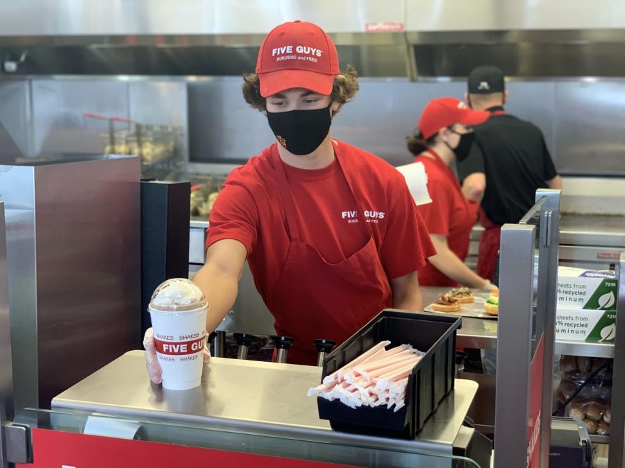 Junior Oliver Smith serves a milkshake to a customer during his shift Sept. 24. Smith has been working at Five Guys for close to a year already and is now having to find new ways to balance work and online schooling.