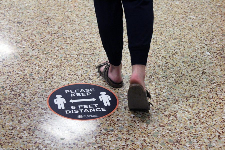 Photo illustration by Talia Lissauer. Please keep 6 feet distance” stickers have been placed throughout the hallways at Park. Other precautionary measure  have been put in place to prevent the spread of COVID-19 including following social distancing guidelines and the use of face coverings. 