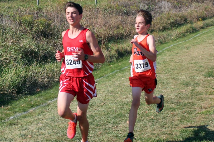 Eighth grader Paxon Myers dashes to overtake Benilde-St. Margaret runner in the last stretch of the race. Myers finished the race with a time of 19:31.