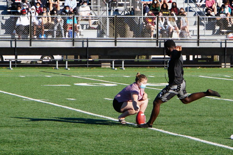 Senior Claudy Zua kicks a football at the pep fest Sept. 9. Fall captains encouraged students to come to their upcoming games.
