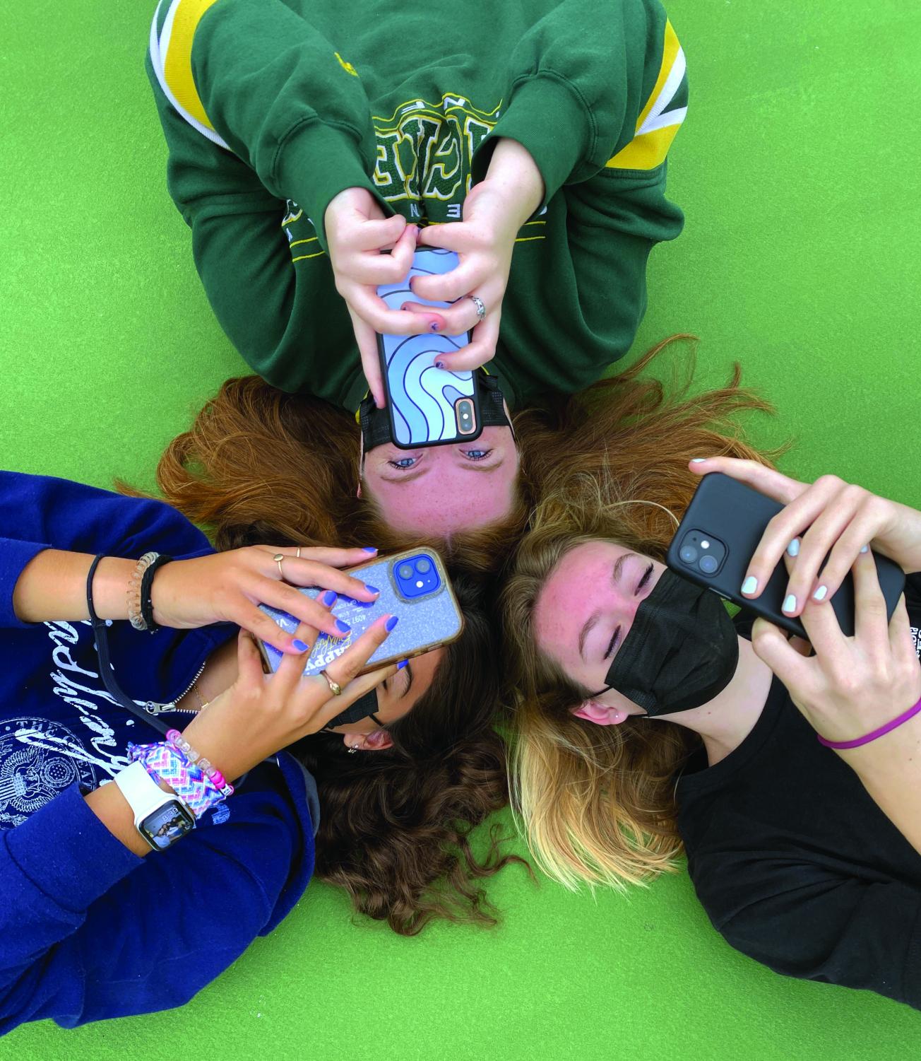 Photo illustration by Crystal Diaz.  Students laying in circle while using phones.