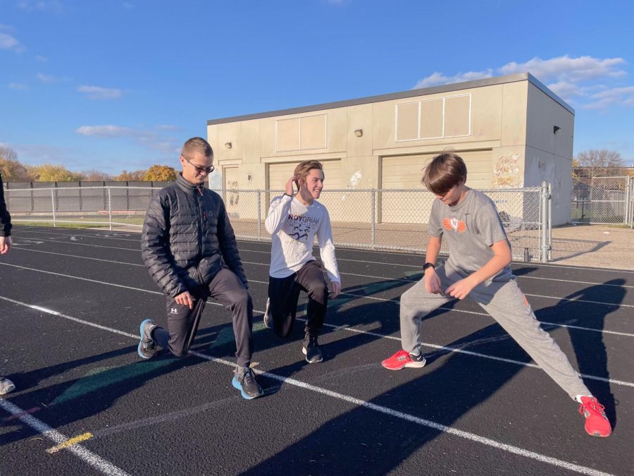 Junior Denly Lindeman stretches out alongside senior Henry Nelson and eight-grader Truman Nelson. The Nike Cross Regionals will be taking place Nov. 14 at Yankton Trail Park in Sioux Falls, South Dakota.
