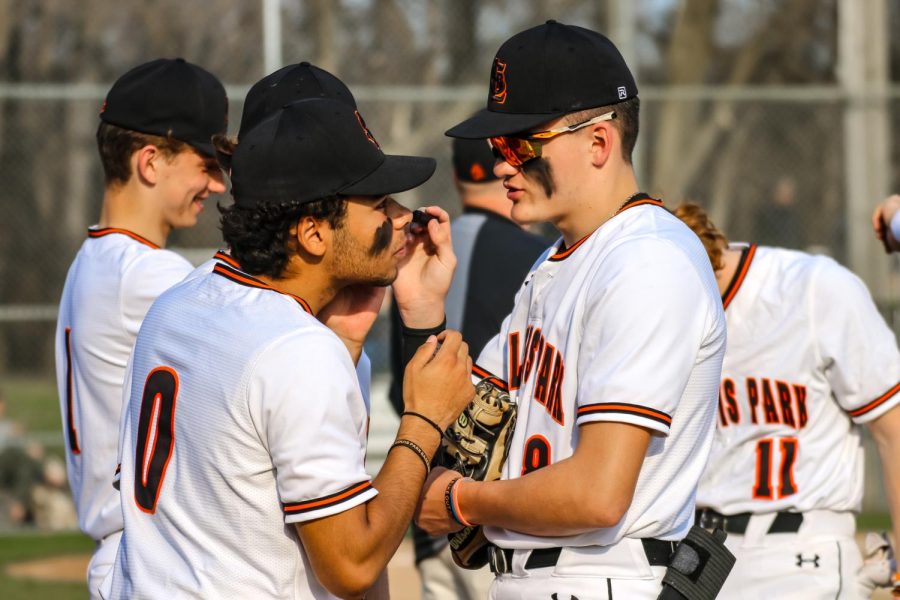 Seniors Stanley Regguinti and Brady Walsh apply eye-black before the game May 4. Eye-black can help reduce glare for athletes in the field as well as provide team spirit.