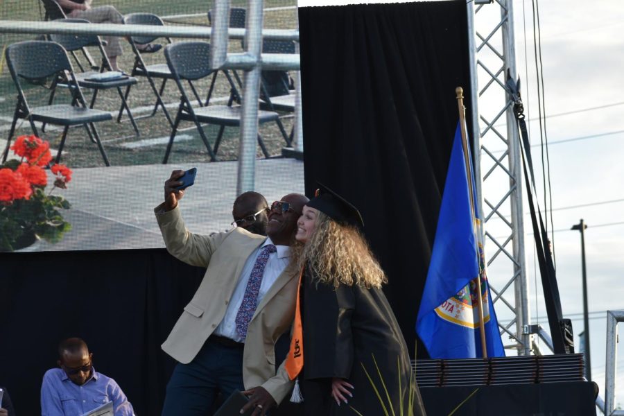 Senior Eva Healey takes a selfie with school board member Ken Morrison June 7. Students announced the names of the graduates as they walked onstage. 
