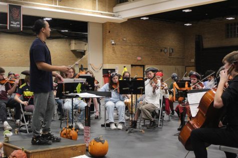 Orchestra teacher Mr. lee leads the orchestra for Halloween themed concert. The Concert was held in the main gym on Oct. 28.