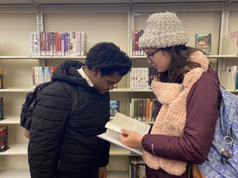Junior Sofia Jerney and sophomore Isaiah Brown browse through the books in the St. Louis Park Library. The library recently reopened and provides a welcoming space for students to check out books and study.