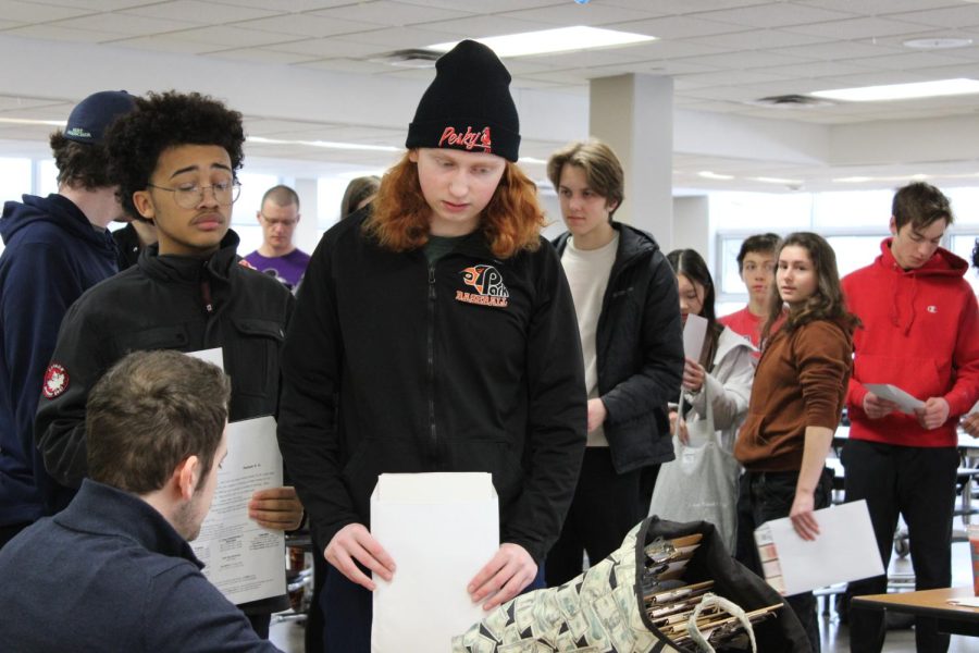 Junior Silas Cowell picks up his coupon cards in the St. Louis Park cafeteria Saturday. Track athletes received coupon cards to sell for their fundraiser March 25.