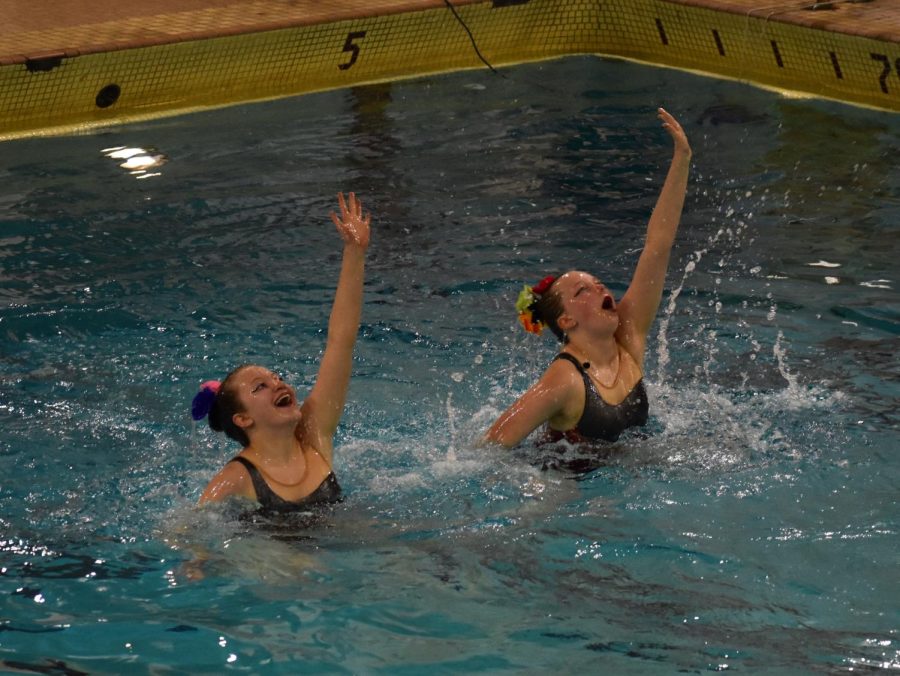 Middle schooler Indigo Schoneman and junior Avery Courneya wave in their duo routine on May 17. The synchronized swimmers swam for a large crowd at the end-of-year performance on Wednesday.