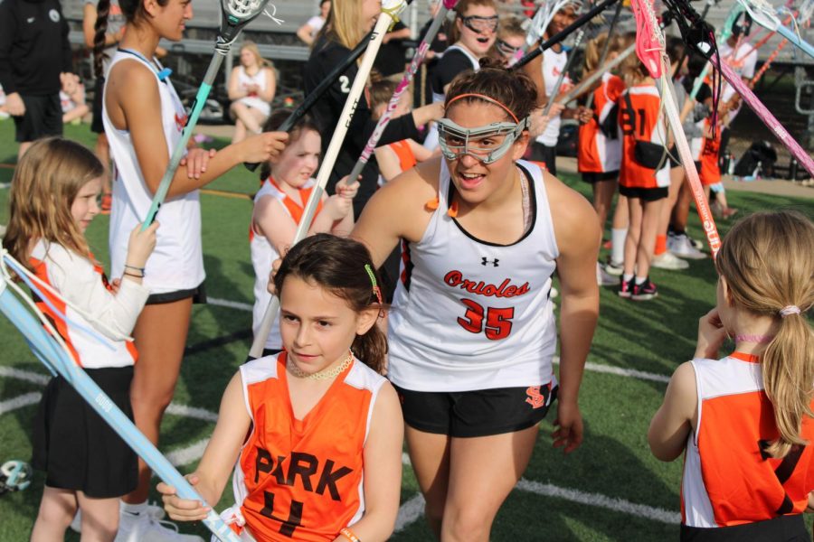 Freshman Gretchen Fandell-Thompson runs out with a youth player before their game May 4. Girls lacrosse hosts an annual youth night to get younger players excited about girls lacrosse.