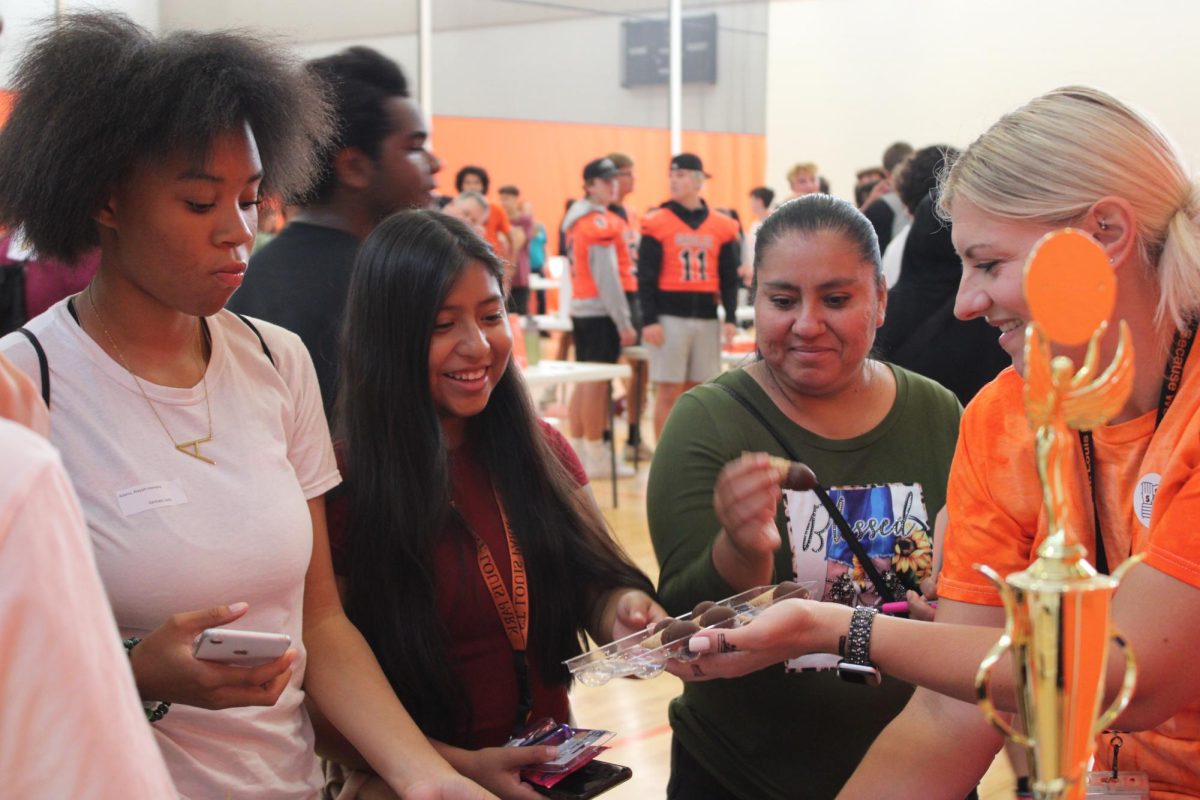 Freshman Madai Claveria-Martinez and Alayjah Admas get ice cream cones from Mrs. Lugo at the DECA booth. During freshman orientation, clubs hosted an activity fair with informational booths Aug 31.