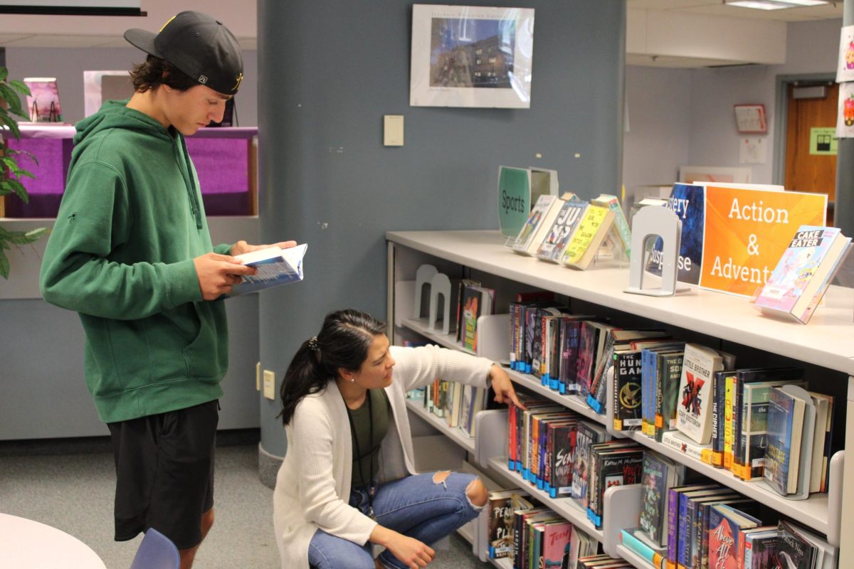 Media Specialist Alison Tsuchiya Theiler helps junior Malik Martin find a book Sept. 18. Library staff have been encouraging English classes to make visits to the new media center.