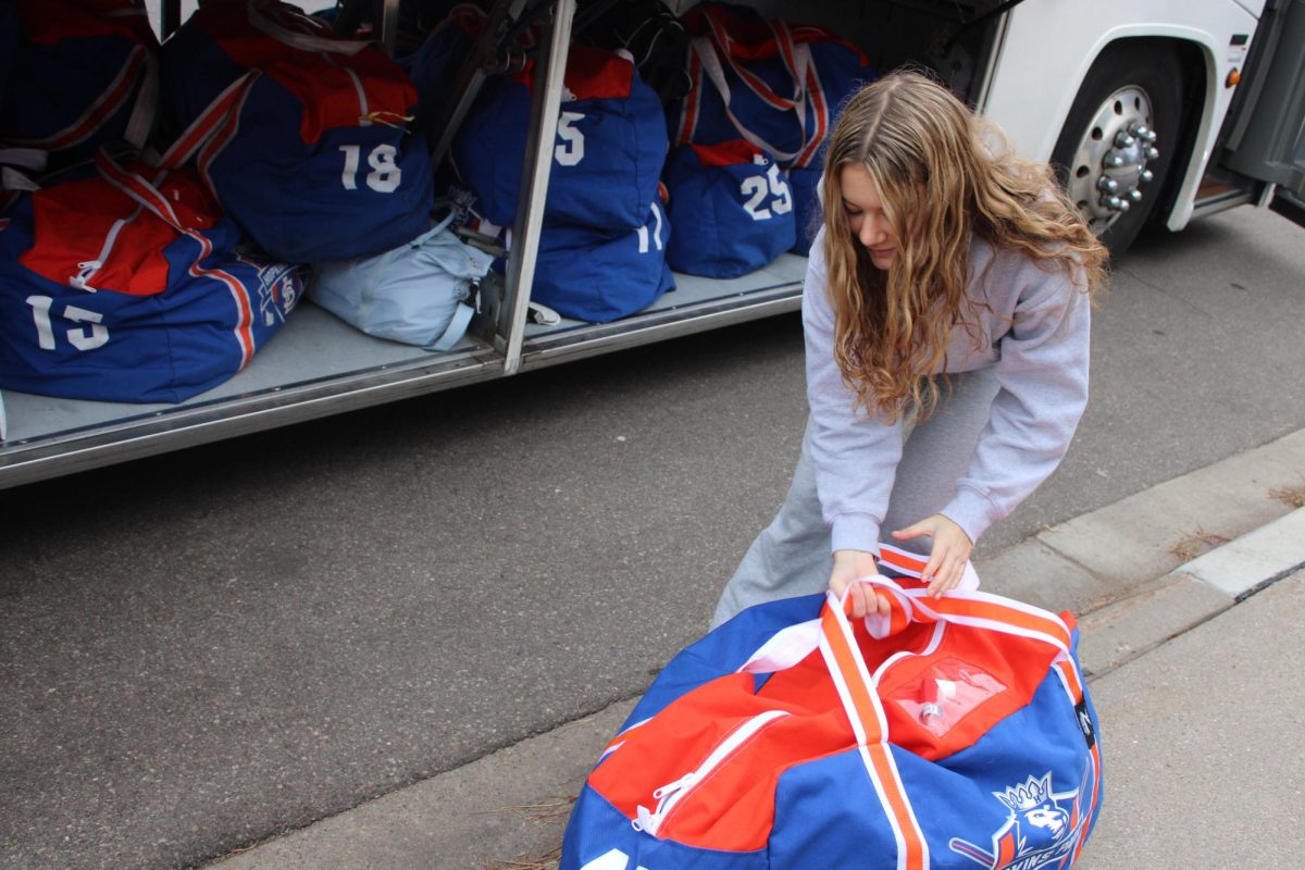 Freshman Lianna Hess loads equipment onto the bus Dec. 8. The girls hockey team went on a trip to the North Shore and played two games.