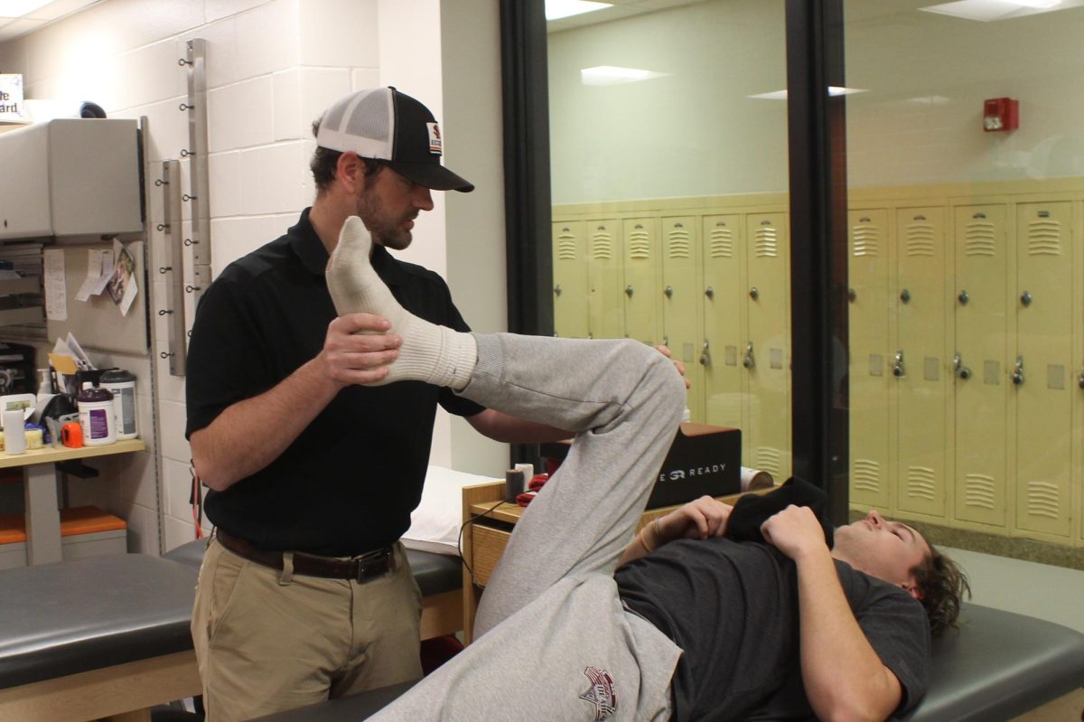 Athletic trainer Josh Broders helps stretch Josh Middleton after school Dec. 13. Broders works with students to recover from and avoid future injuries.  