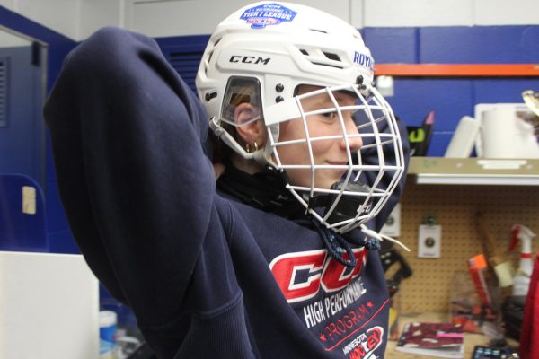 Eighth-grader Hazel Schenkelberg puts on her neck guard before practice Feb. 12. Requiring these guards will heavily increase safety among young players.