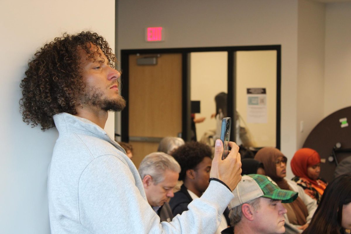 Community activist and Park alumni Lavish Metzger holds up his phone live streaming the Park School Board superintendent finalist interviews on March 13. Metzger posted on social media, calling for community members to show up to the meeting.