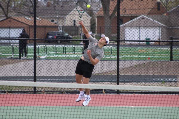 Junior Isaac Joseph serves the ball to an opponent April 18. The match against Benilde St. Margaret’s ended in a loss of 2-5.