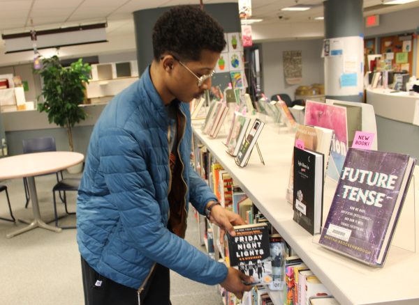 Sophmore Abdikadir Mohamed grabs book in the school library April 17. the LMC is very underused this year as it is currently going under construction.