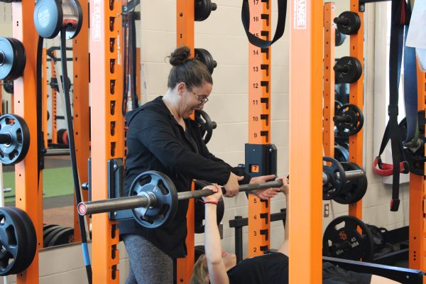 Coach Jessica Gust assists sophomore Lila Frank on the bench press May 27. Summer strength and conditioning has recently added a new girls-only season.