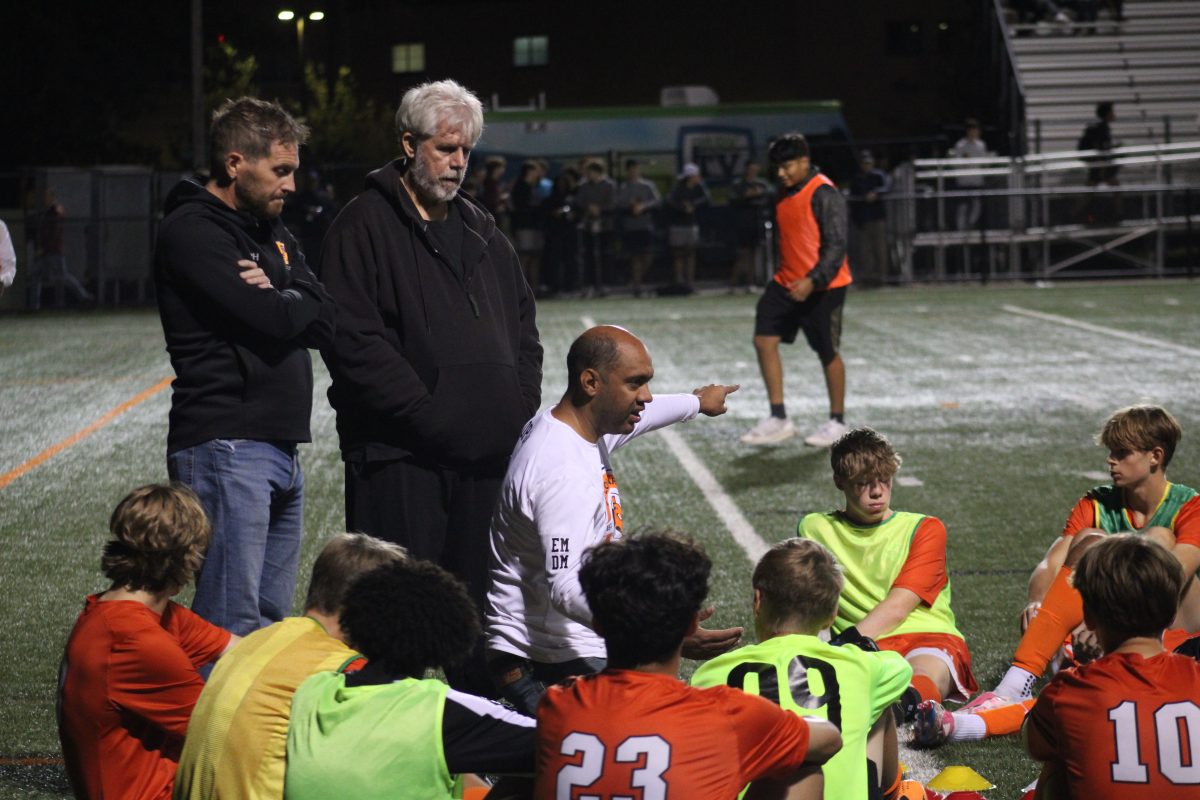 Head boys' soccer coach Anson Opara goes over plays during halftime Oct. 9.  Coaches are leaders who help guide players throughout their high school athletic career.