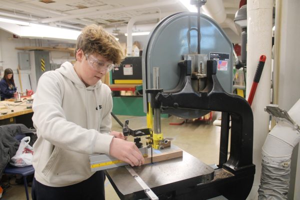 Freshman Judah Lissauer uses a blade saw to cut blocks of wood in Woodworking Dec. 12. The pieces of wood will be carved into pens as a Summative project.