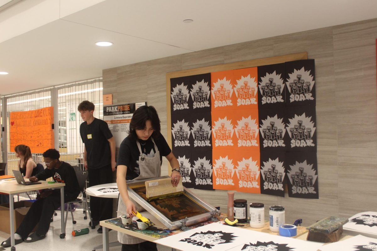Senior Aurora Pascual prints posters with SOAR’s new logo at their potluck and fundraiser event Dec. 17. The logo was designed by Pascual and voted for by the rest of SOAR.