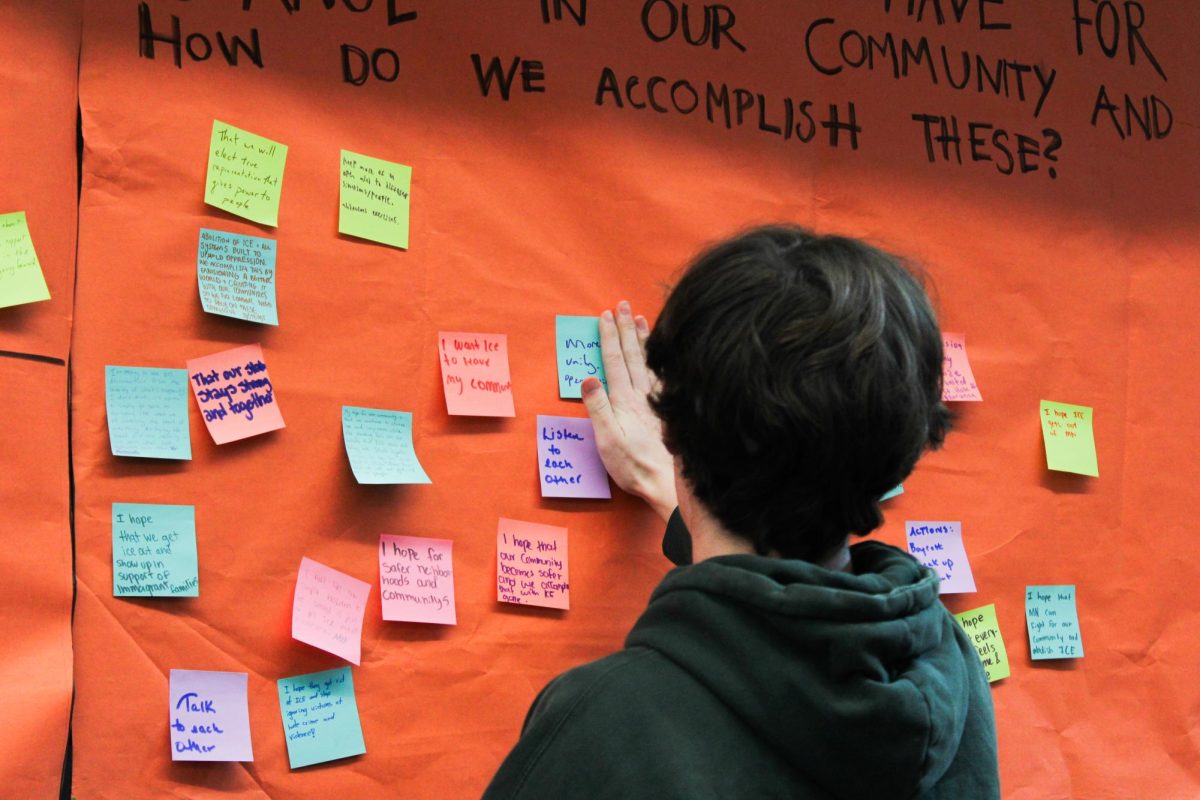 Student places a post-it note with a message to SLP communities on poster Jan. 12. SOAR held a memorial for Renee Nicole Good to raise awareness and allow for discussion with students.