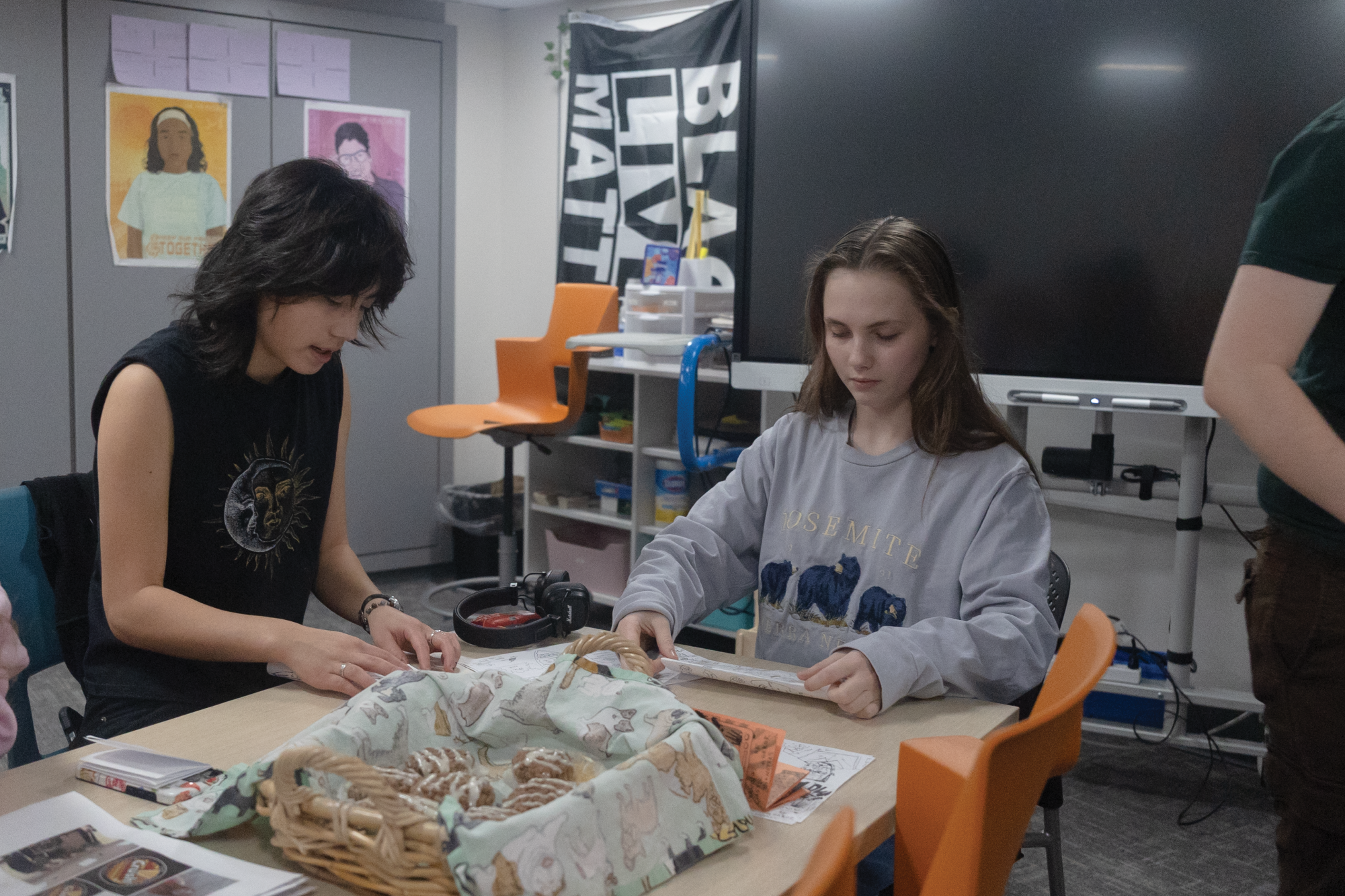 Seniors Aurora Pascual and Katherine Healy talk while folding zines Nov. 20. Zines allow freedom of expression and can be made to convey any message the maker wants to send.
