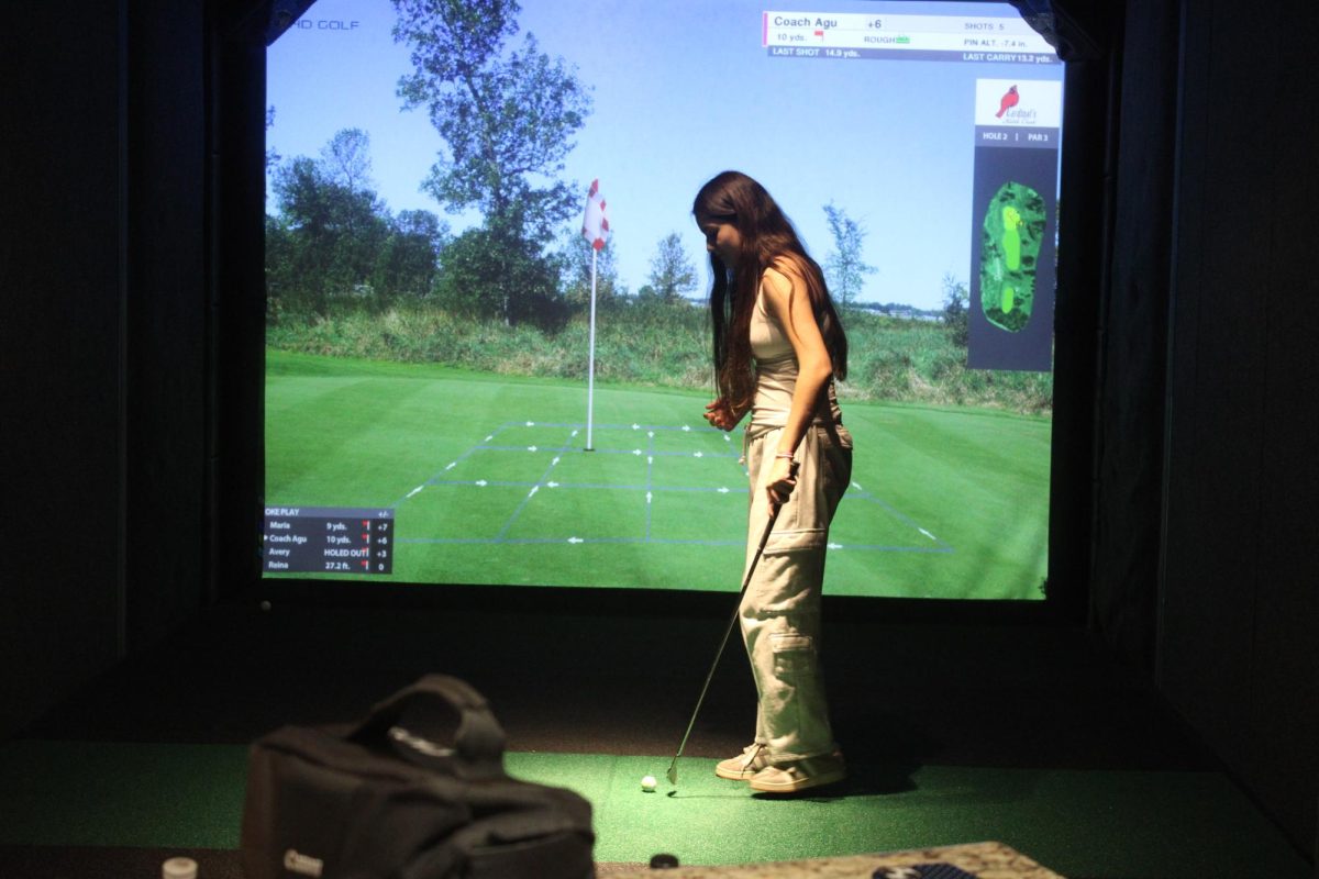 Sophomore Agustina Jerney prepares to swing her club at the Life Time simulator March 26. Players use simulators to practice golf skills indoors and gain technical info on their performance.