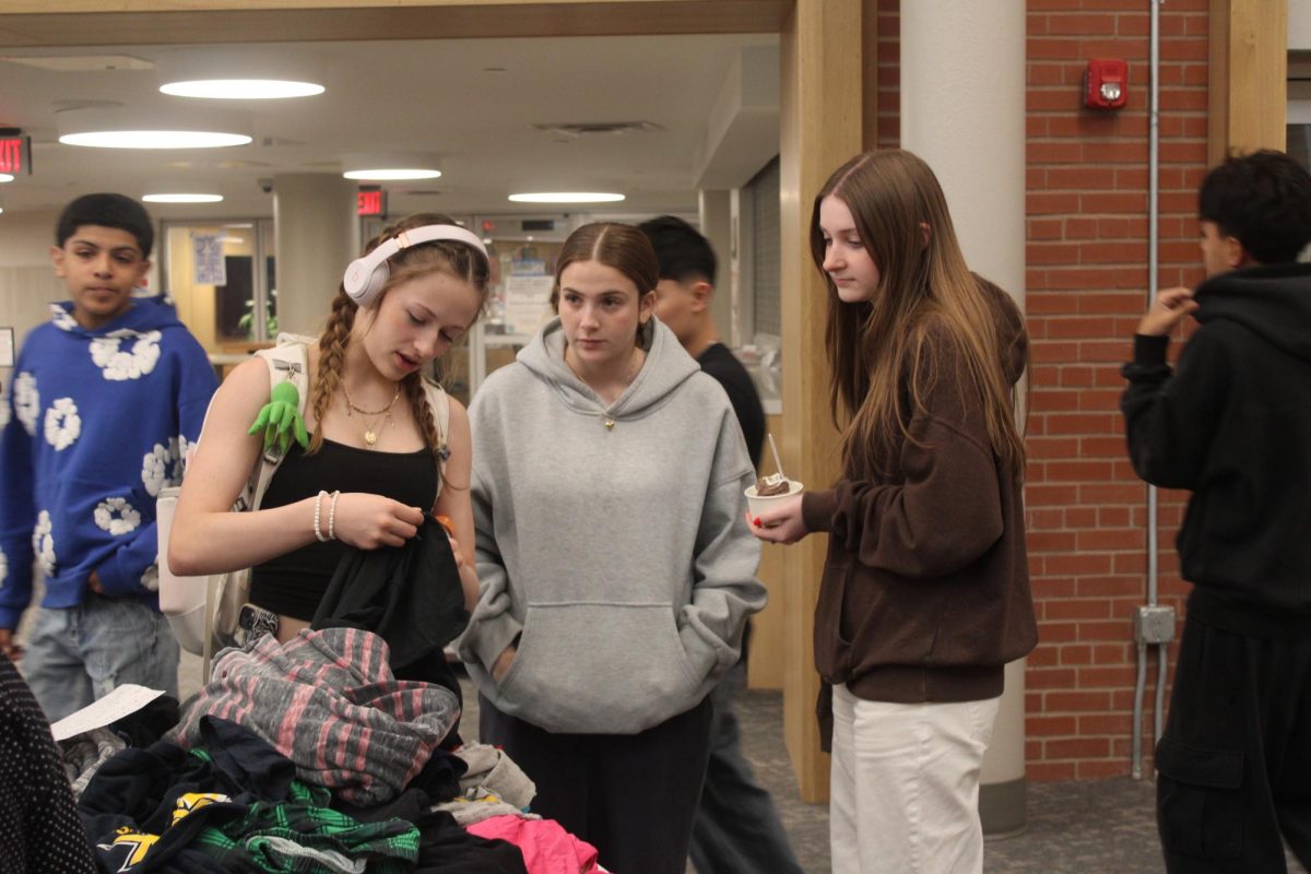 Freshman Francesca School, Ainsley Carter and Alexandra Charloff attend the Girls United clothing drive May 1. Students look around at the clothing and shoes that they can take from the provided tables.