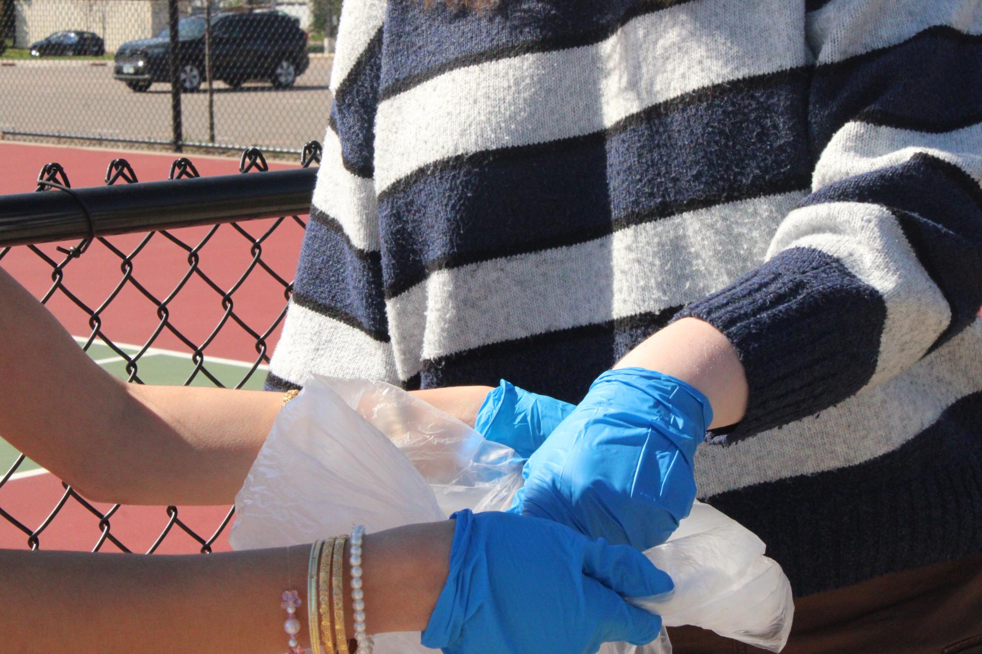 Junior Asha Ferrán-Sapatnekar and senior Bailey Schneeberg work together to clean up litter around Park’s campus April 24. The trash pickup was one of the collaborative, change-making efforts included in Environmental Club’s Earth Week events.
